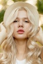 Close up beauty portrait of a beautiful blonde woman with curly blonde hair with healthy skin and straw hat Royalty Free Stock Photo