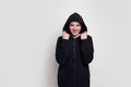 Frontal portrait of a happy brunette girl in a black sweater with hood on her head, isolated on white background. Royalty Free Stock Photo