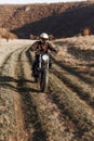 Frontal portrait of a motorcyclist equipped with helmet and protective clothing, drives a motorcycle, at sunset.