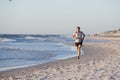 Athletic fit and strong runner man training on Summer sunset beach in sea shore running and fitness workout in sport and healthy l Royalty Free Stock Photo