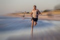 Athletic fit and strong runner man training on Summer sunset beach in sea shore running and fitness workout in sport and healthy l Royalty Free Stock Photo