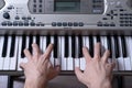 Frontal rear view of women`s hands playing the keys of the electronic piano