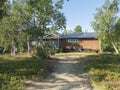 Frontal view of one of Saltoluokta Fjallstation STF mountain lodge in birch forest with two backpacks on the bench