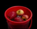 Frontview of Group of apples kept in salt water in a plastic bowl to detox and to reduce the oxidation, isolated on black.