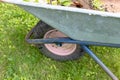 Frontwheel of wheelbarrow standing on the lawn of a garden, gardening and horticulture concept Royalty Free Stock Photo