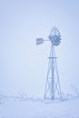 Frost covered windmill on a foggy winter morning