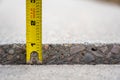 Frost heave crack in residential concrete sidewalk with tape measure