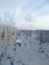 Frost structure on window against the background of city during winter day. Close up snowy glass on blurred background of building