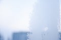 Frost structure on window against the background of sky during winter day. Close up snowy glass on blurred background. Frosty