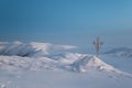 Frosted cross in snow covered mountains