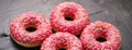 Frosted sprinkled donuts, sweet pastry dessert on rustic wooden background, doughnuts as tasty snack, top view food brand flat lay