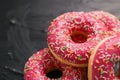 Frosted sprinkled donuts, sweet pastry dessert on rustic wooden background, doughnuts as tasty snack, top view food brand flat lay