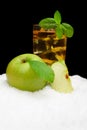 Frosty apple juice,ice cubes and apple with leaves on black on snow Royalty Free Stock Photo