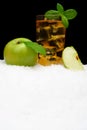 Frosty apple juice,ice cubes and apple with leaves on black on snow Royalty Free Stock Photo