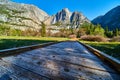 Frosty boardwalk in shade as sun hits cliffs and Upper Yosemite Falls in background Royalty Free Stock Photo