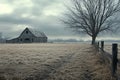 Frosty field with a rustic barn and a bare tree under a hazy sky Royalty Free Stock Photo