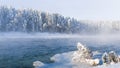 Frosty fog over winter river with snow and forest on bank. First ice on lake Royalty Free Stock Photo