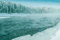 Frosty fog over winter river with snow and forest on bank. First ice on lake Royalty Free Stock Photo