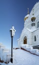 A frosty lantern stands at the building of the Orthodox Church. A thick layer of frost covers the glass of the lantern. The temple