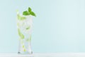Frosty mint lemonade with green leaf, ice cubes, striped straw, mineral water in elegant glass on white wood table, mint color. Royalty Free Stock Photo