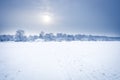 Frosty morning winter snow field landscape with distant forest on horizon in cold frost winter day in soft blue color