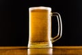 Frosty mug of beer close up on wooden table against black background. Royalty Free Stock Photo