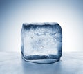 Cold blue ice block melting into water puddle on metal surface