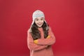 Frosty weather. Winter outfit. Cute model enjoy winter style. Small child long hair wear hat red background. Wintertime
