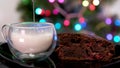 frothing milk with cappuccino maker in glass mug Brownie cake with cherries Christmas tree, drops of milk splashes