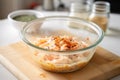 frothy batter being mixed with chopped kimchi in glass bowl