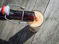 Frothy dark beer pouring into tall glasses from a brown glass bottle in summer garden on rustic wooden table Royalty Free Stock Photo