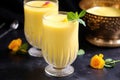 a frothy mango lassi in a glass with a golden straw