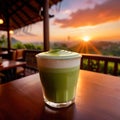 a frothy matcha latte with a stunning sunrise in the background.