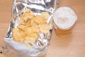 Frothy pint of lager and open bag of potato chips Royalty Free Stock Photo