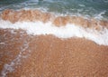 Frothy waves of the sea on the sandy beach. Foamy wave rolls