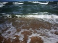 Frothy waves of the sea on the sandy beach. Foamy wave rolls