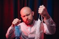 Frowned man in white shirt holding gauze masks in hands on red and blue background. Emotion of assertiveness and determination