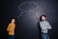 Frowning angry couple thinking identically over background of chalkboard