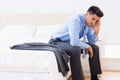Frowning businessman sitting at edge of bed Royalty Free Stock Photo