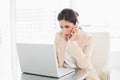 Frowning businesswoman working with a laptop on the phone Royalty Free Stock Photo