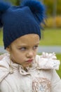 frowning girl with hat in transitional season outdoors