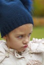 frowning girl with hat in transitional season outdoors