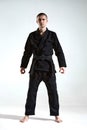 Frowning guy in black kimono fighter posing on white studio background with copy space, mix fight concept Royalty Free Stock Photo