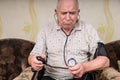 Frowning senior man monitoring his blood pressure