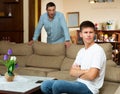 Frowning teen boy with berating father