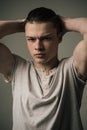 Frowning teenage boy isolated on gray background, street, hooligan, troublemaker. Young man with muscular torso and Royalty Free Stock Photo