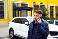 Frowning tense sullen or sad concentrated young caucasian 34 years old man with goatee beard talks on smartphone on street near