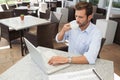 Frowning young businessman working at laptop drinking coffee Royalty Free Stock Photo