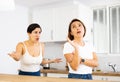 Woman listening listlessly to reprimanding from sister in home kitchen