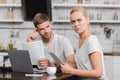 frowning young woman holding papers and looking at camera while using laptop with boyfriend Royalty Free Stock Photo